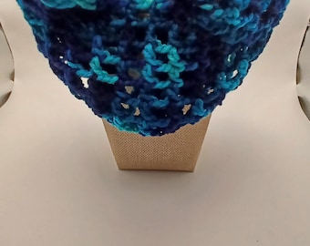 Puede incluir: Una bufanda tipo cuello tejida a ganchillo con un patrón de hilo jaspeado en tonos azul marino oscuro, azul real y turquesa brillante. El accesorio está elaborado con un diseño de punto abierto y aireado que crea una textura con volantes.