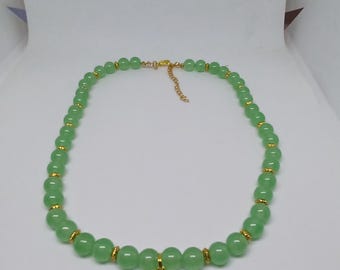 Puede incluir: Un collar de cuentas verdes con detalles dorados y un colgante de estrella de mar dorado. El collar está hecho de pequeñas cuentas redondas de color verde claro. Los detalles dorados son pequeñas cuentas cilíndricas.