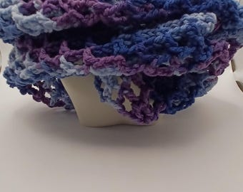 Puede incluir: Una bufanda infinita de ganchillo grueso con un patrón de hilo jaspeado en tonos morado intenso, azul real y azul cielo claro. El accesorio presenta un diseño de punto abierto, aireado y texturizado que crea un aspecto voluminoso.