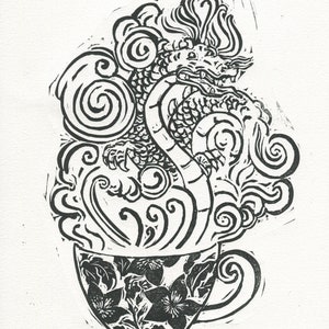 May include: Black and white line art print of a dragon emerging from a teacup. The dragon is curled up in the cup, with its head and tail sticking out. The cup is decorated with floral designs.