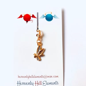 Puede incluir: Encanto de color dorado con una abeja estilizada con alas. El encanto está unido a un cierre de langosta dorado. El encanto se muestra en una tarjeta blanca con el texto "heavenlyhellelements@msn.com" y "Heavenly Hell Elements".