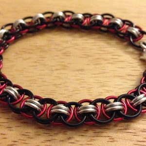 Peut inclure: Un bracelet en maille de chaîne noir, rouge et argent avec un fermoir argenté.