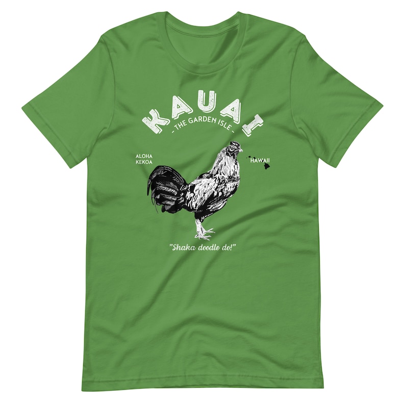 May include: Green t-shirt with a white graphic of a rooster and the text "Kauai - The Garden Isle" with the words "Aloha Kekoa" and "Hawaii" on either side of the rooster. The text "Shaka doodle do!" is below the rooster.
