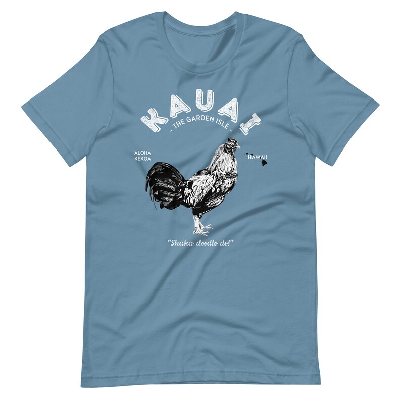 May include: A light blue t-shirt with a white graphic of a rooster and the text "Kauai - The Garden Isle - Aloha Kekoa - Hawaii - Shaka doodle doi!"
