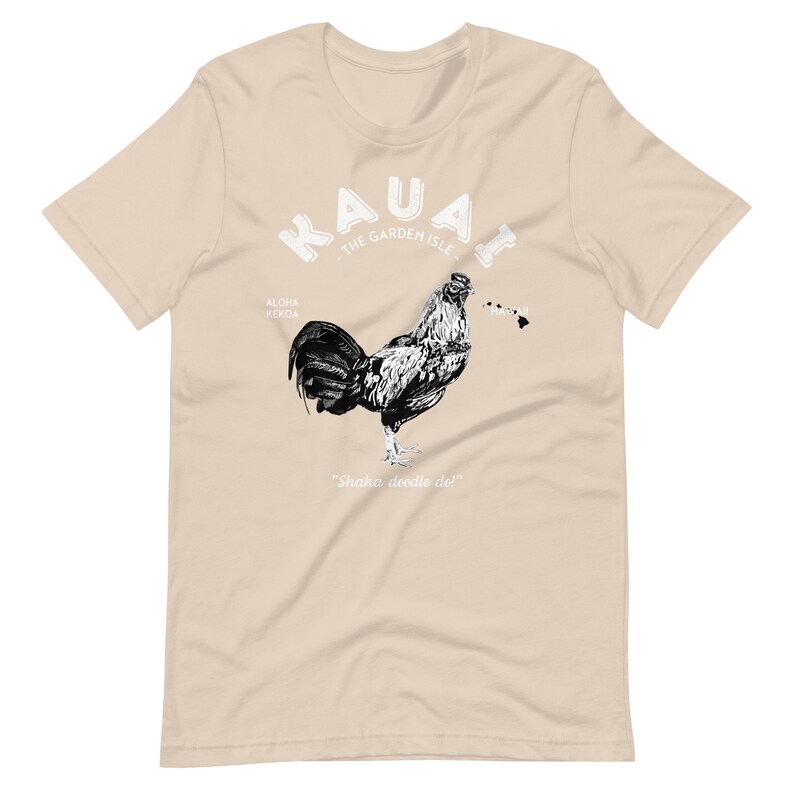 May include: A tan t-shirt with a black and white illustration of a rooster. The text "Kauai - The Garden Isle" is above the rooster. The text "Aloha Kekoa" is to the left of the rooster and the text "Shaka doodle doo!" is below the rooster.