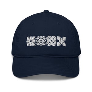 May include: A navy blue baseball cap with white embroidered geometric designs. The designs are arranged in a row across the front of the cap.