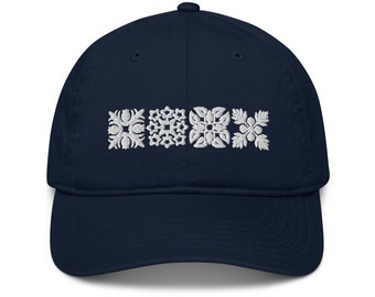 May include: A navy blue baseball cap with white embroidered geometric designs. The designs are arranged in a row across the front of the cap.