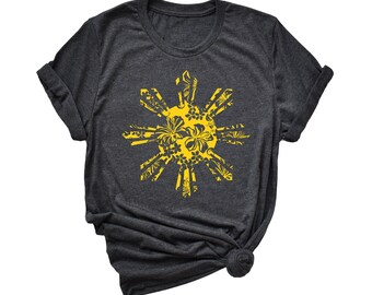 Puede incluir: Una camiseta gris oscuro con un diseño de sol floral amarillo. El sol tiene ocho rayos y está lleno de un patrón floral.