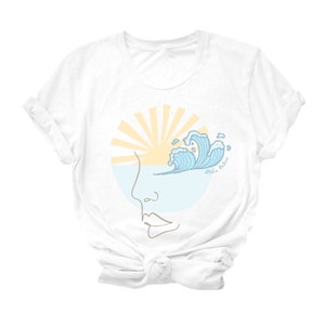 Puede incluir: Camiseta blanca con un gr&aacute;fico de un sol poni&eacute;ndose sobre una ola con el texto "Aloha vibes" en un c&iacute;rculo.
