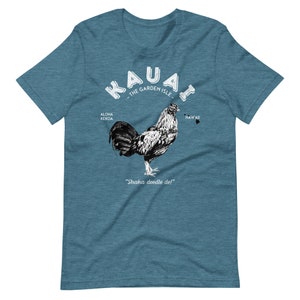 May include: A teal blue t-shirt with a white graphic of a rooster and the text "Kauai - The Garden Isle - Aloha Kekoa - Hawaii - Shaka doodle do!"
