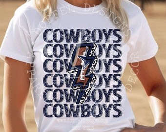 Op de afbeelding: Wit T-shirt met een afbeelding van een bliksem met een luipaardprint en het woord "COWBOYS" dat vijf keer wordt herhaald. Het shirt wordt gedragen door een vrouw met een witte cowboyhoed.