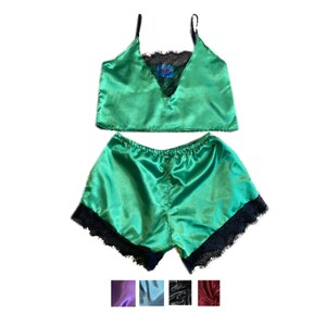 May include: Green satin pajama set with a camisole top and shorts. The top has black lace trim and thin straps. The shorts have black lace trim along the hem. Additional color options are shown below the set.