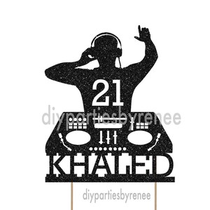 May include: Black glitter cake topper depicting a DJ silhouette wearing headphones, with the number 21 and the name "Khaled." The DJ is raising one hand. The topper is mounted on wooden sticks, ideal for a birthday party.
