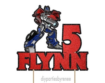 Può includere: Topper per torta di personaggio Transformers rosso e blu con il numero 5 e il nome Flynn. Il topper è su un bastoncino di legno.