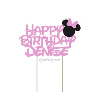May include: Pink glitter cake topper with the words "Happy Birthday Denise" and a black Minnie Mouse head with a pink bow.
