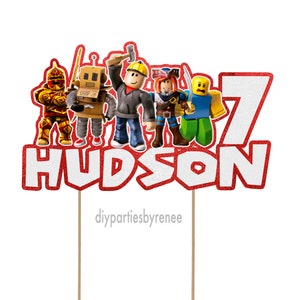 May include: Red and white cake topper with the name "HUDSON" and the number "7" in white with red glitter. There are five Roblox characters on the topper, including a knight, a robot, a construction worker, a pirate, and a character wearing a blue shirt. The topper is on two wooden sticks.