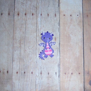 May include: Purple and pink cartoon dragon figurine with a striped body and wings.