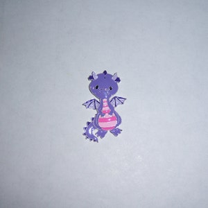 May include: Purple dragon charm with pink stripes and wings. The dragon is holding a pink ball in its front paws.