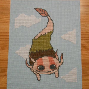 May include: Cross-stitch embroidery of an axolotl with a green and brown leafy tail, pink body, and black eyes. The axolotl is floating in a blue sky with white clouds.