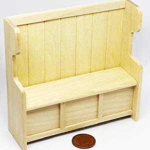 May include: A miniature wooden bench with a back and three storage compartments. The bench is made of light-colored wood and has a simple, classic design. A penny is placed in front of the bench for scale.