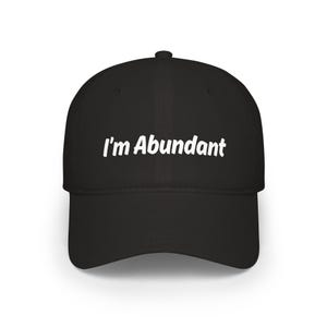 May include: A black baseball cap featuring the white text I'm Abundant embroidered across the front panel. The cap has a structured crown, a curved brim, and a button at the top centre. The design is centred on the front of the headwear.