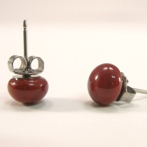 May include: A pair of red stud earrings with silver posts and butterfly backs.