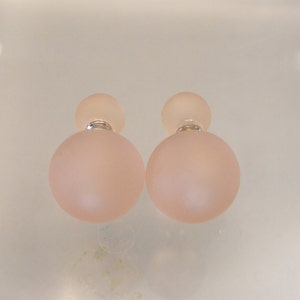 May include: A pair of double-sided earrings with frosted pink glass spheres. The earrings have a silver post and a small silver bead on the top of each sphere.