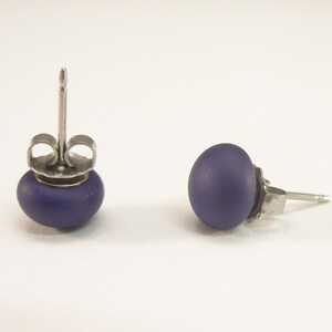 May include: A pair of purple stud earrings with silver posts and backs.