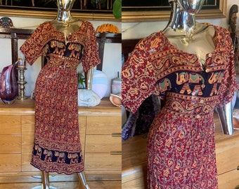 May include: A long red and black dress with an elephant print. The dress has a button-up front and short sleeves.
