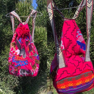 May include: A pink backpack with colorful embroidered designs and a drawstring closure. The backpack has a geometric pattern on the back and a woven strap.