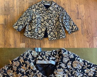 May include: A black and gold brocade jacket with a floral pattern. The jacket has a single button closure and a label that reads "I. Magnin."
