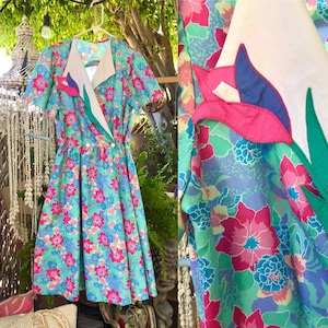 May include: A vintage floral print dress with a white collar and a pink and green floral applique on the collar. The dress has short sleeves and a full skirt.