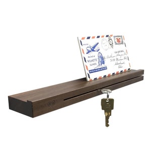 Peut inclure: Un porte-clés en bois brun foncé avec une fente pour le courrier et un crochet pour les clés. Le porte-clés porte les mots "Live, Love, Laugh" gravés sur le devant. Une carte postale vintage et un jeu de clés sont affichés sur le porte-clés.