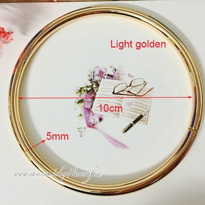Könnte beinhalten: Ein hellgoldener Metallring mit einem Durchmesser von 10 cm und einer Breite von 5 mm.