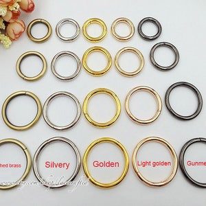 May include: Assortment of metal rings in various finishes, including brushed brass, silvery, golden, light golden, and gunmetal. The rings are arranged in rows by color.