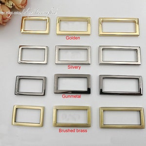 May include: Four rows of metal rectangular rings in different finishes: golden, silvery, gunmetal, and brushed brass.