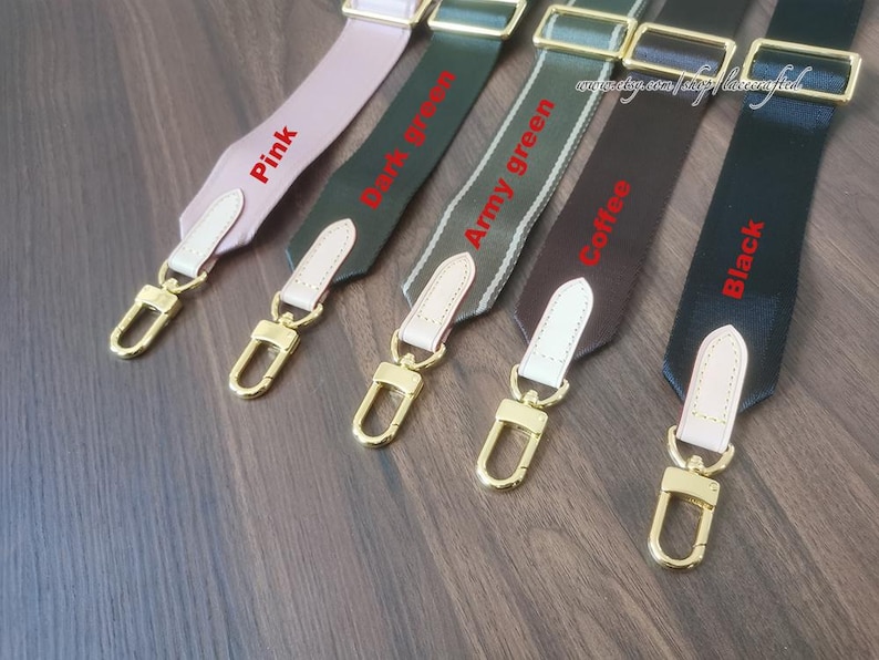 K&ouml;nnte beinhalten: F&uuml;nf verschiedene farbige Riemen mit goldenen Metallschlie&szlig;en. Die Riemen sind mit "Pink", "Dunkelgr&uuml;n", "Army Green", "Kaffee" und "Schwarz" beschriftet.
