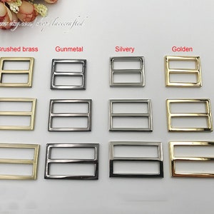 May include: A set of 10 metal slider buckles in four different finishes: brushed brass, gunmetal, silvery, and golden. Each buckle has two horizontal bars.