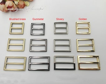 May include: A set of 10 metal slider buckles in four different finishes: brushed brass, gunmetal, silvery, and golden. Each buckle has two horizontal bars.
