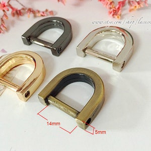 Könnte beinhalten: Vier D-Ringe aus Metall in verschiedenen Ausführungen: Gold, Silber, Antikmessing und Schwarz. Die Ringe haben einen Durchmesser von 3,5 cm und eine Breite von 1,2 cm.