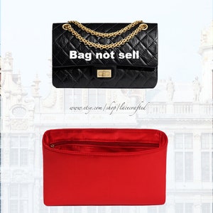 Può includere: Una borsa a mano trapuntata nera con una tracolla a catena dorata e una chiusura dorata. La borsa è foderata in raso rosso. Il testo "Bag not sell" è stampato sulla parte anteriore della borsa.