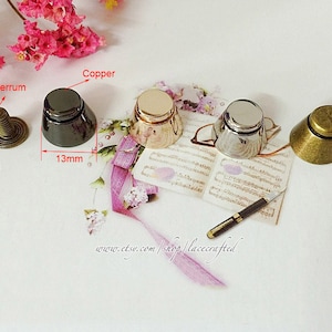 May include: Four metal decorative caps in different finishes: copper, silver, gold, and black. The caps are 13 mm in diameter and have a 4 mm screw base. The caps are shown on a piece of paper with music notes and a pen.