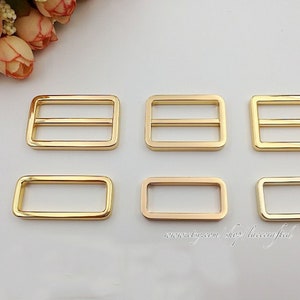 Puede incluir: Seis hebillas deslizantes de metal dorado de diferentes tamaños. Las hebillas son rectangulares con una o dos barras en el centro.