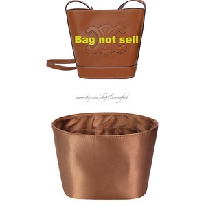 May include: A brown leather bucket bag with a top handle and a shoulder strap. The bag has a large embossed logo on the front and the text "Bag not sell" in yellow.