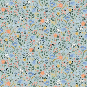 Op de afbeelding: Een lichtblauwe stof met een herhalend patroon van kleine bloemen in koraal-, geel- en wittinten, afgewisseld met groene bladeren, stengels en takjes lavendel. Het ontwerp is dicht en bedekt het gehele oppervlak gelijkmatig.
