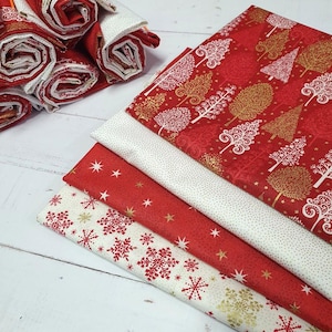Può includere: Una collezione di pezzi di tessuto piegati con motivi festivi. I disegni includono stampe di fiocchi di neve rossi e bianchi, alberi stilizzati dorati e rossi e piccoli motivi a stella. I tessuti sono stratificati e arrotolati.