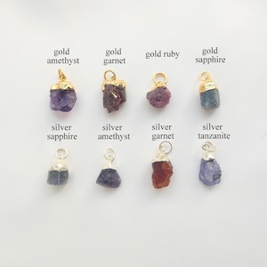 Peut inclure: Collection de pendentifs en pierres précieuses avec des détails en or et en argent. Les pendentifs comprennent de l'améthyste, du grenat, du rubis et du saphir dorés, ainsi que du saphir, de l'améthyste, du grenat et de la tanzanite argentés. Chaque pierre est brute.