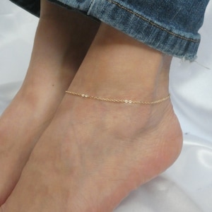 Può includere: Un braccialetto di catena dorato su una caviglia.