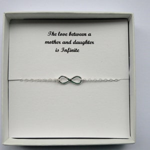 May include: A white box containing a silver infinity charm bracelet. The box has a card that reads "The love between a mother and daughter is infinite."