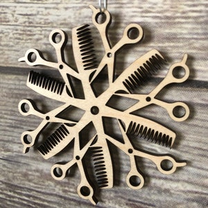 May include: A wooden Christmas ornament shaped like a snowflake, made from multiple pairs of scissors and combs.